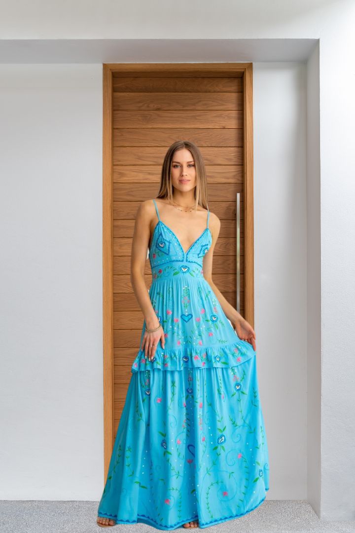 Woman wearing a blue dress standing in a room with wooden paneling.