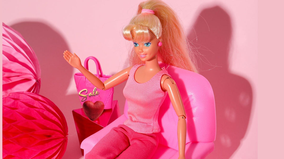 Barbie skitting in pink chair on a pink background