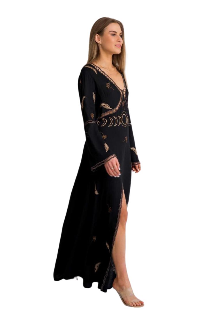 Woman wearing a black long-sleeve dress with gold patterns on a white background