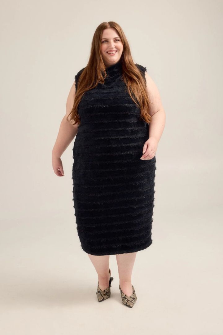 Woman wearing a black textured dress against a plain background
