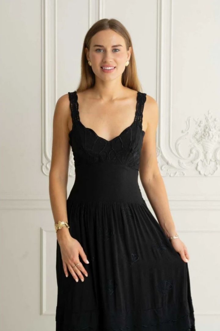 woman in black embroidered dress in white room