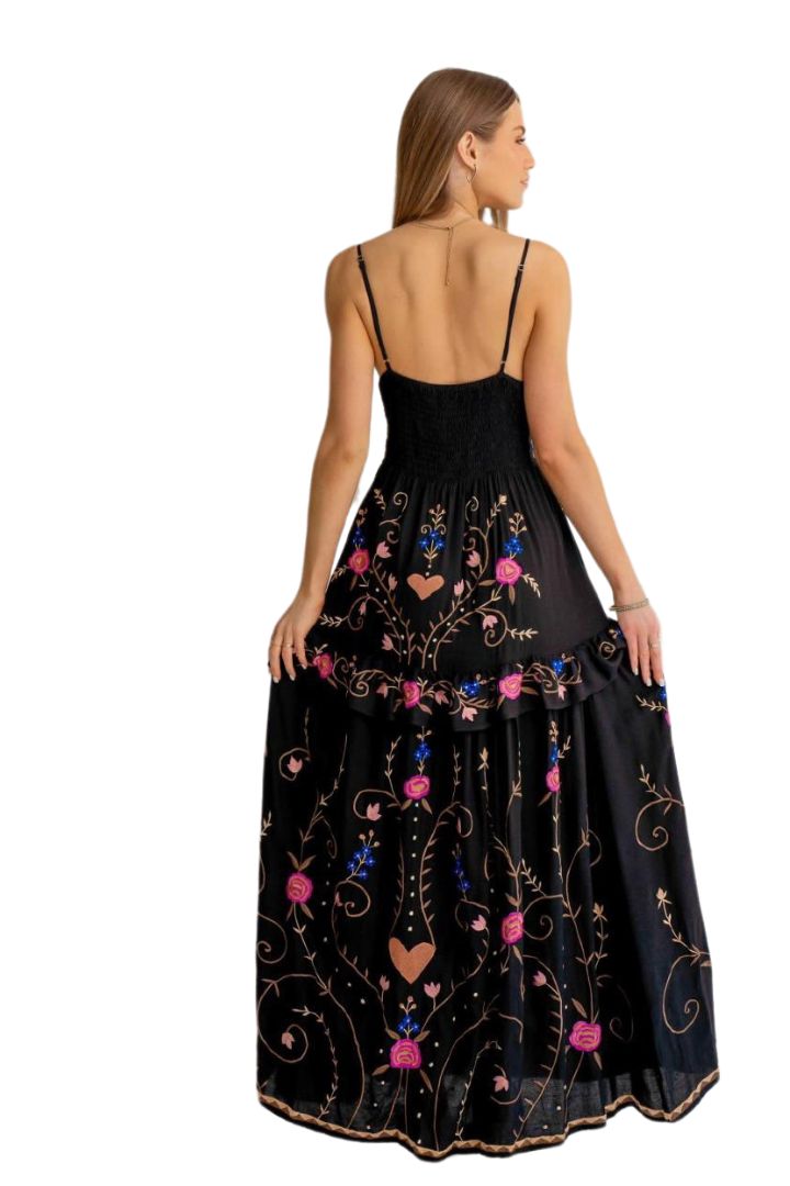 Woman wearing a black dress with colorful floral embroidery on a white background