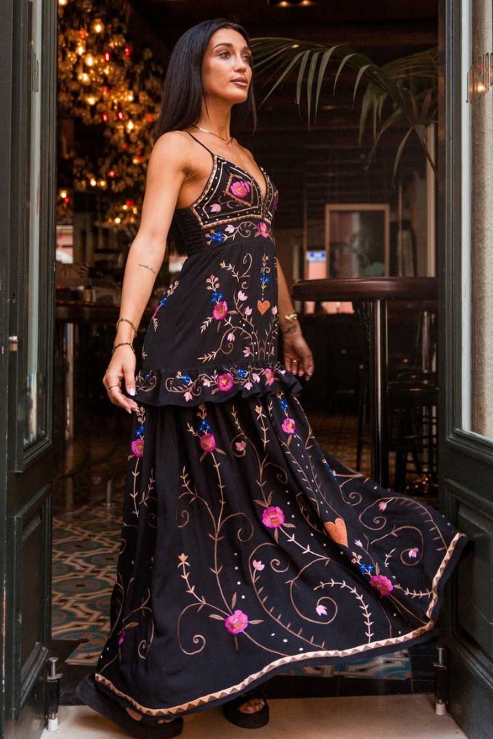 Woman wearing a black embroidered dress in an indoor setting