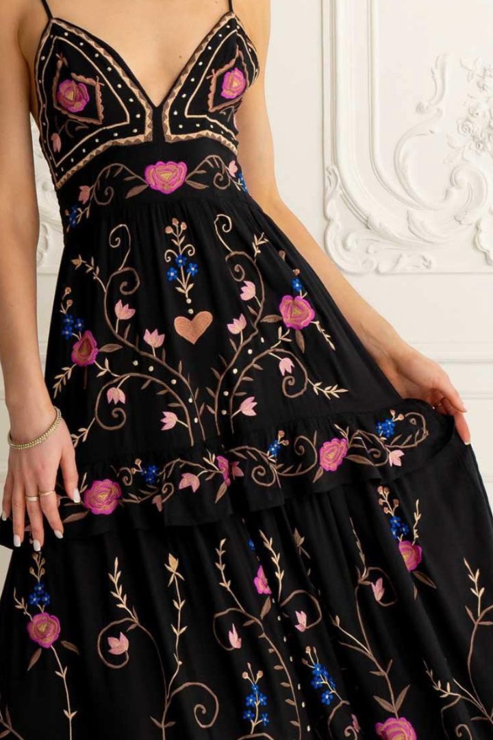 Black dress with floral embroidery on a white wall background