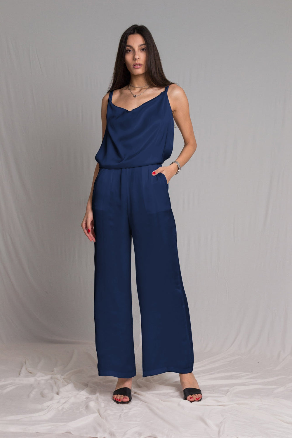Midnight blue satin jumpsuit with a cowl neckline thin straps and a risque low back